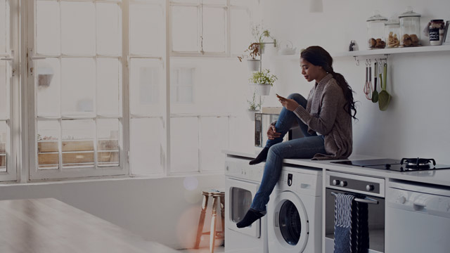 Young woman sitting on washing machine small overlay