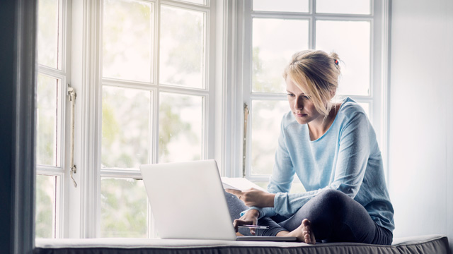 Woman sitting by her window working with her computer