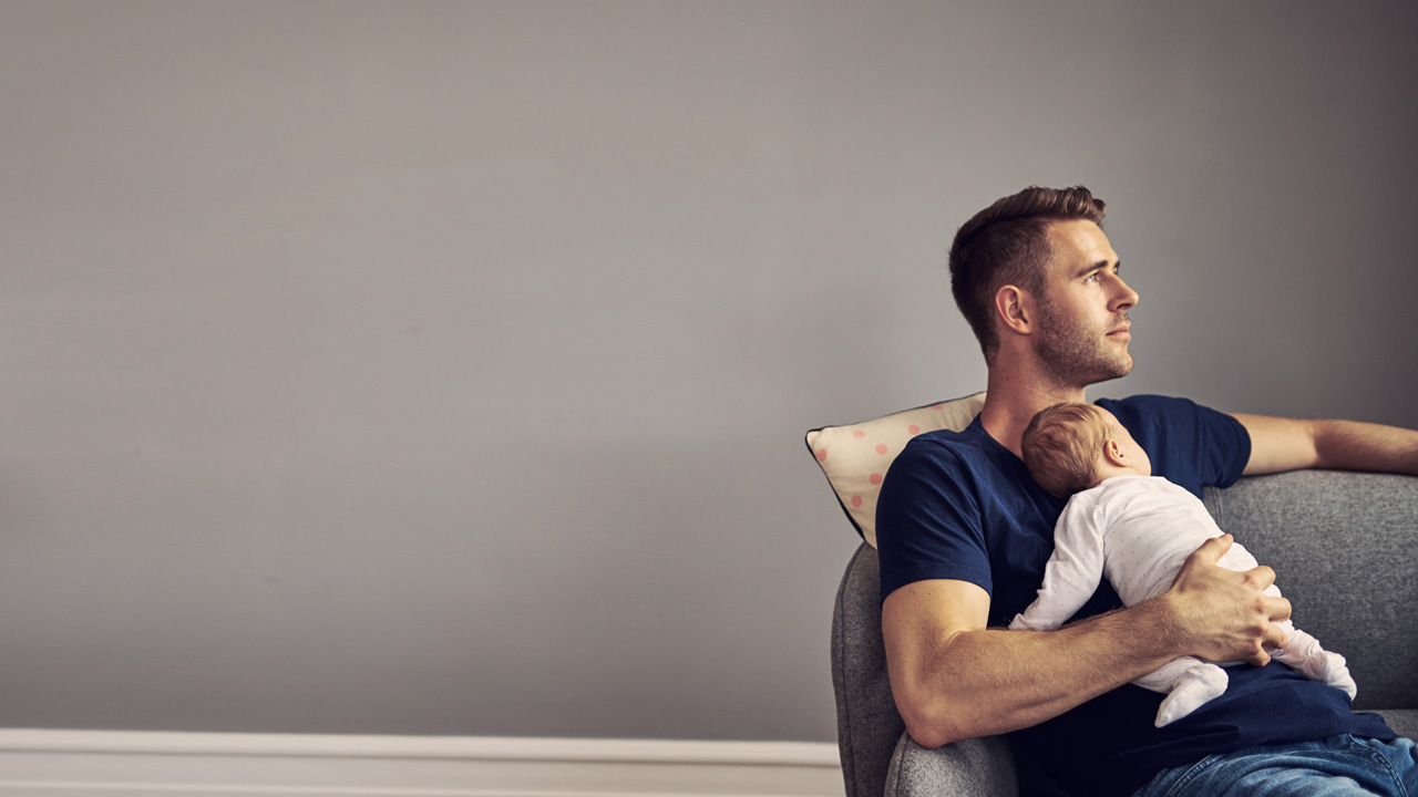 Man resting on sofa with kid resting on his chest 
