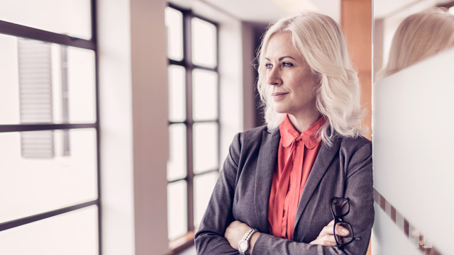 Business woman smiling and looking outside a window