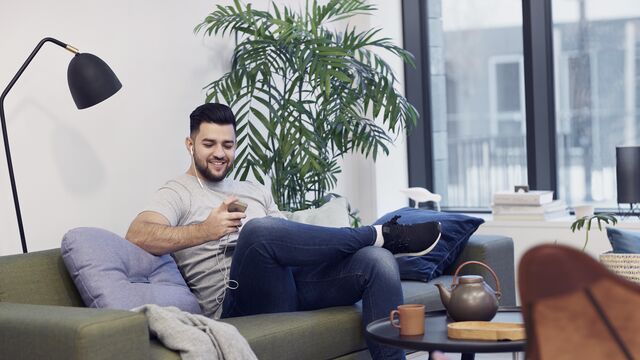 Man smiling while looking at his mobile at home.