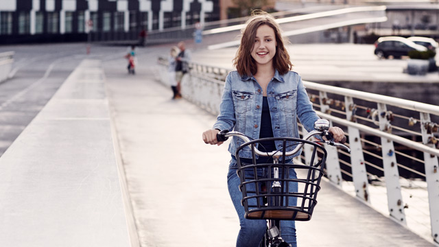 A young girl is biking in a city summertime.