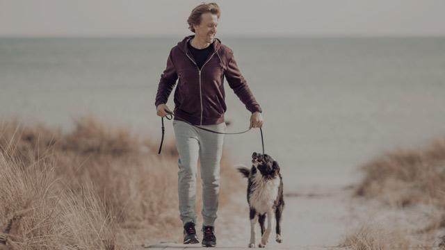 man walking with dog on the beach small overlay