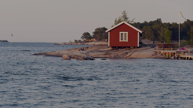 Red wooden summer house at the seaside small overlay