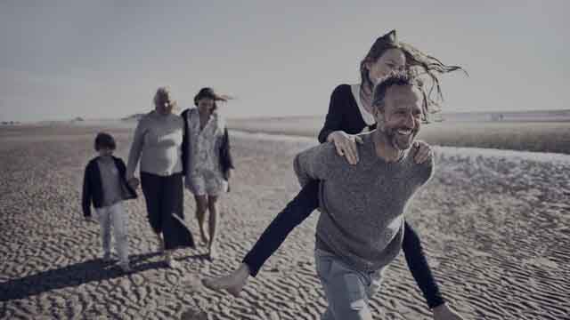 Three generations walking on beach small overlay